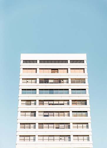 apartment building white building with glass windows blue sky